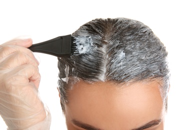 Photo of Young woman dyeing her hair against white background, closeup