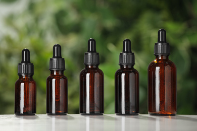 Photo of Glass bottles on white table against blurred green background