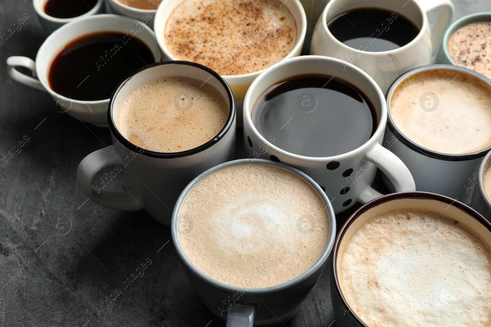 Photo of Many cups of different coffees on slate table