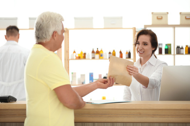 Photo of Pharmacist giving medicine to customer in drugstore