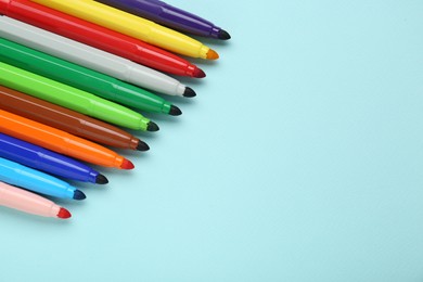 Photo of Different colorful markers on light blue background, space for text