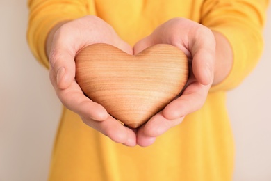 Photo of Man holding wooden heart in hands on color background, closeup