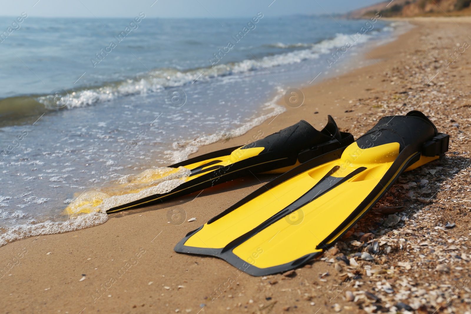 Photo of Pair of yellow flippers on sand near sea, closeup