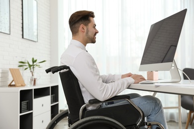 Portrait of man in wheelchair at workplace. Space for text