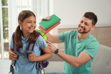 Photo of Father helping his daughter to get ready for school at home