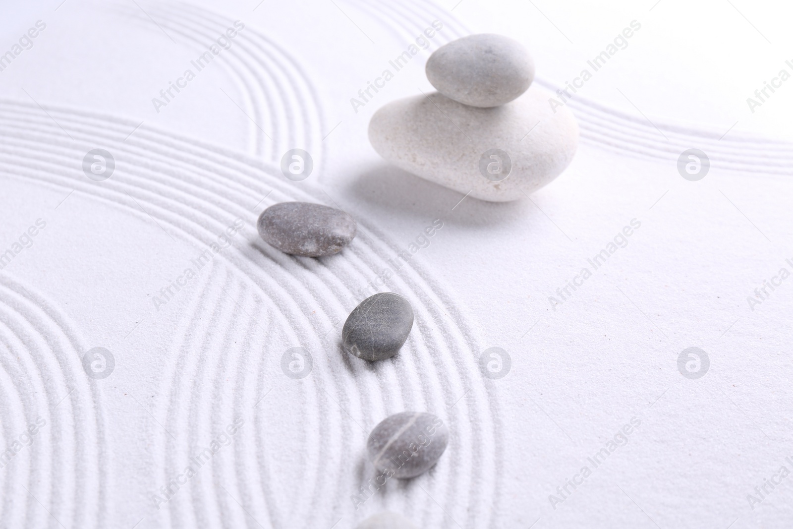 Photo of Zen garden stones on white sand with pattern