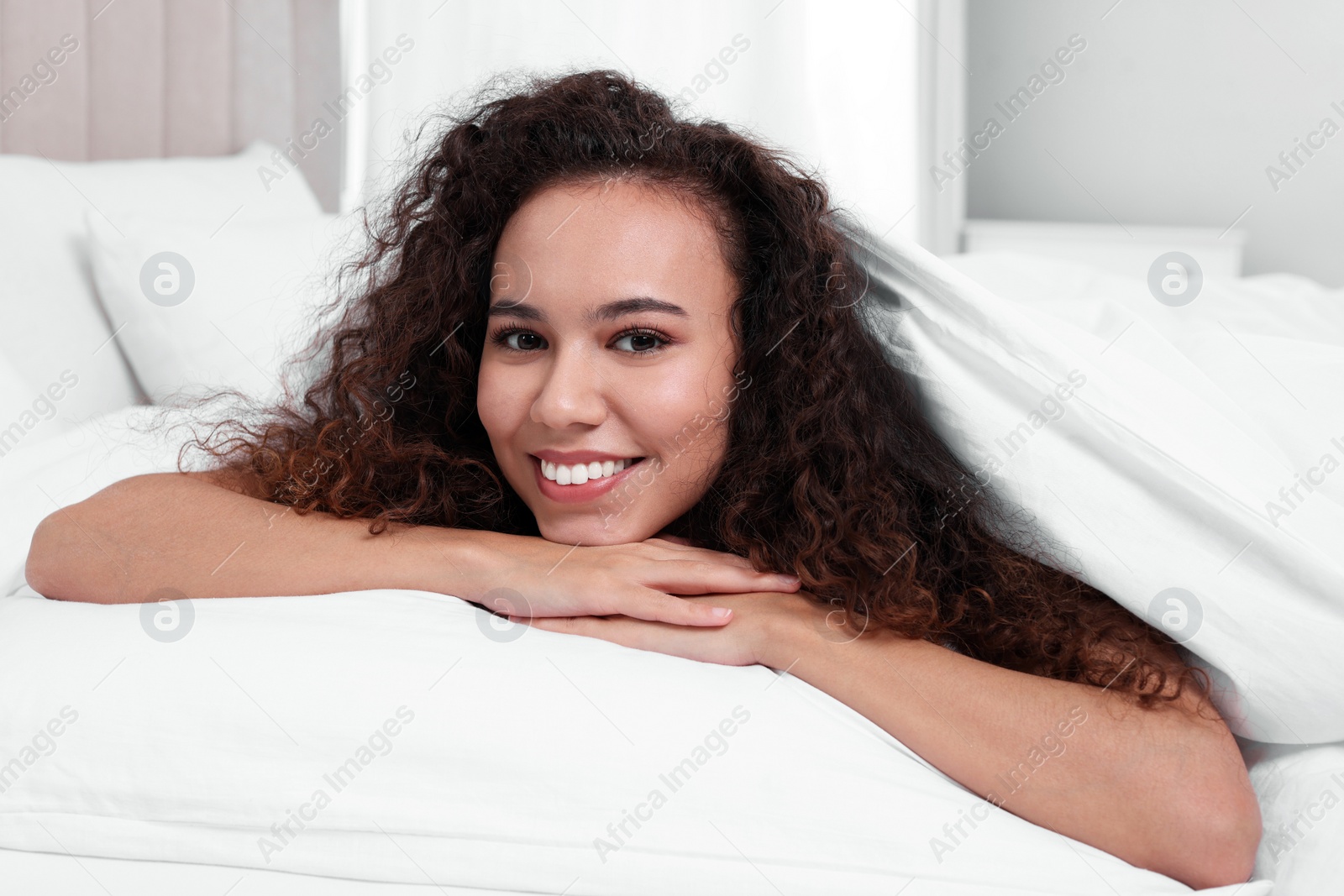 Photo of Happy African American woman lying on bed at home