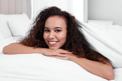 Happy African American woman lying on bed at home