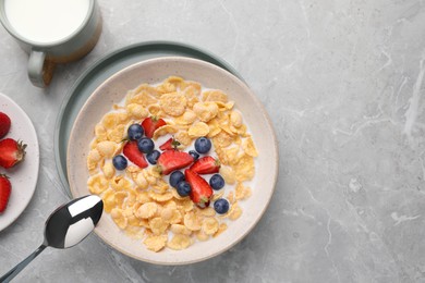 Photo of Bowltasty crispy corn flakes with milk and berries on light grey table, flat lay. Space for text