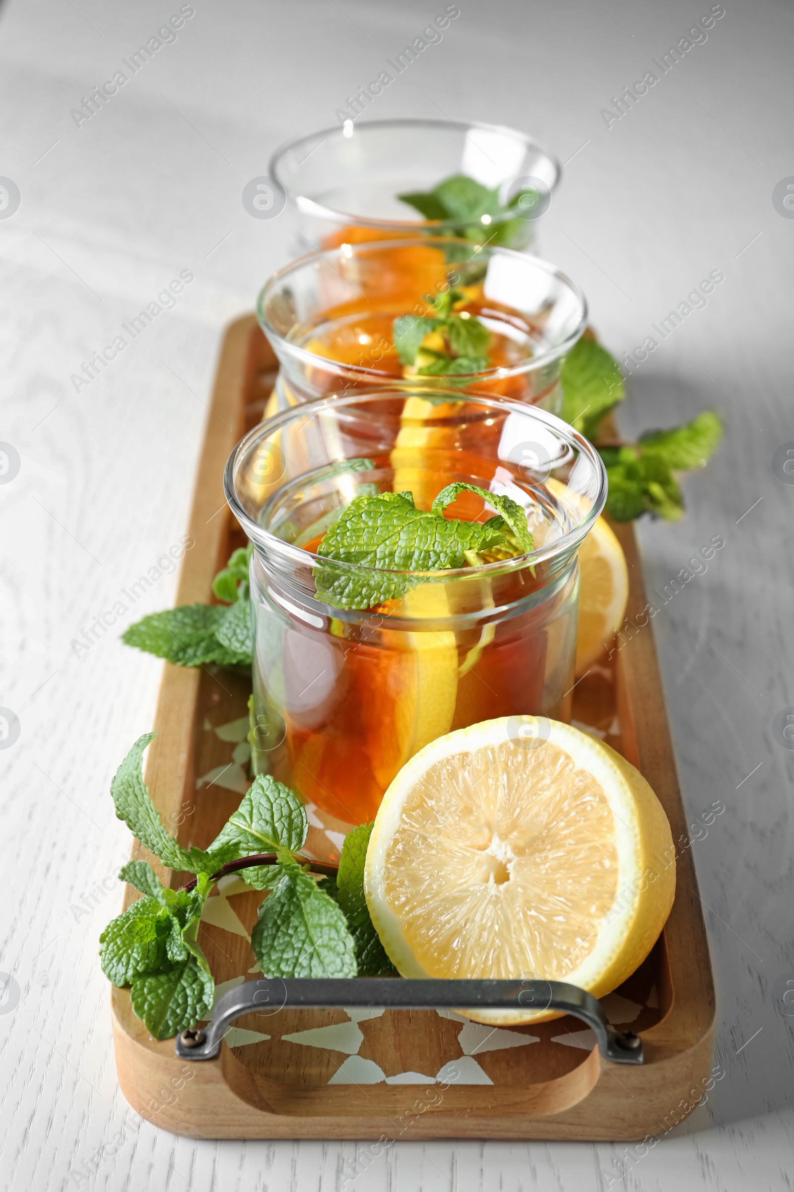 Photo of Wooden tray with hot tea in glasses on table, closeup