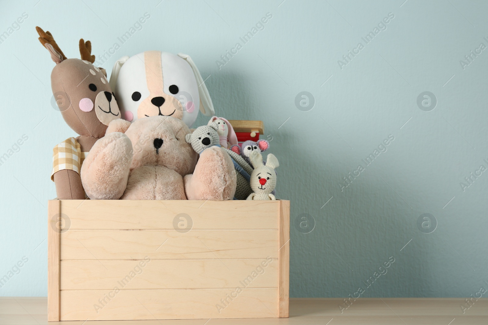 Photo of Crate with different toys on wooden table. Space for text