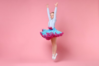 Photo of Cute little girl dancing on pink background