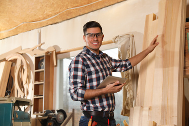 Photo of Professional carpenter with tablet in modern workshop