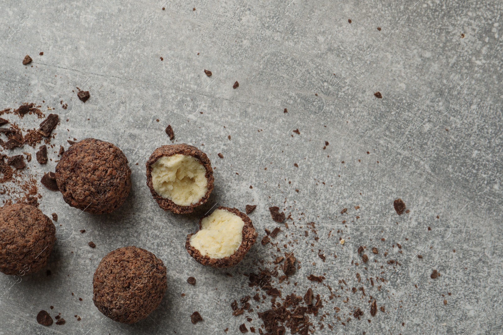 Photo of Many delicious chocolate truffles on grey table, flat lay. Space for text