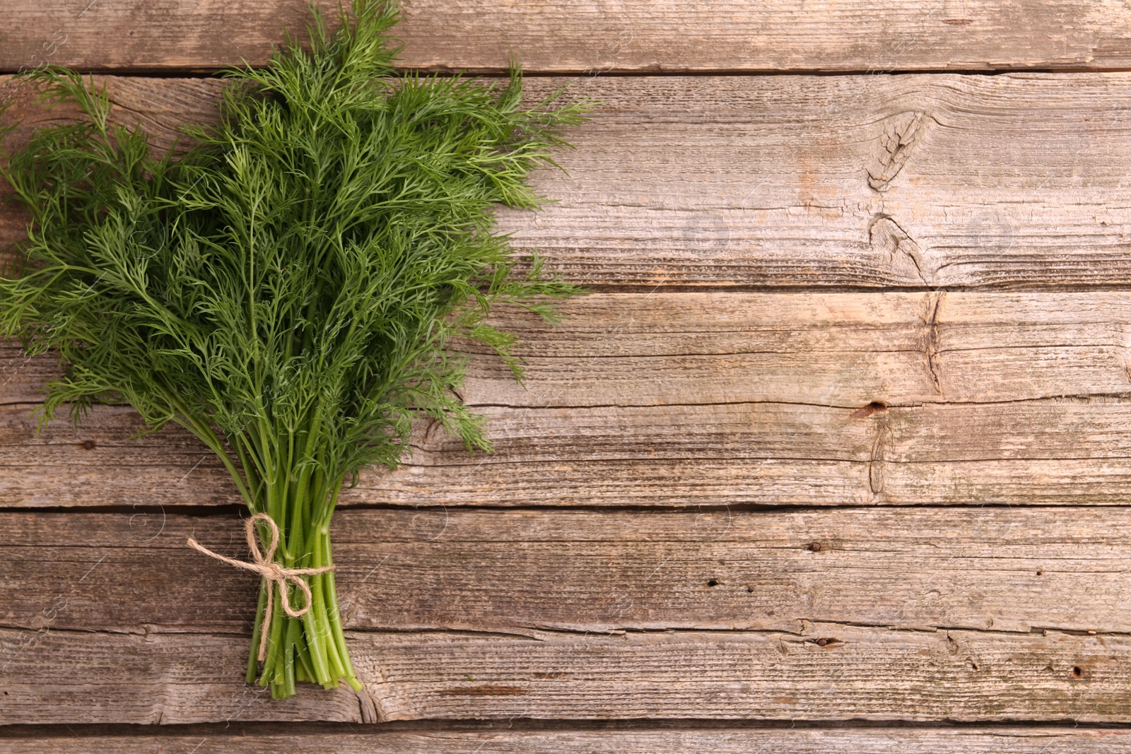 Photo of Bunch of fresh dill on wooden table, top view. Space for text