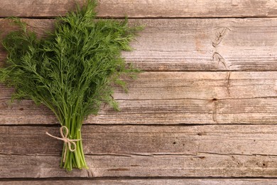 Photo of Bunch of fresh dill on wooden table, top view. Space for text