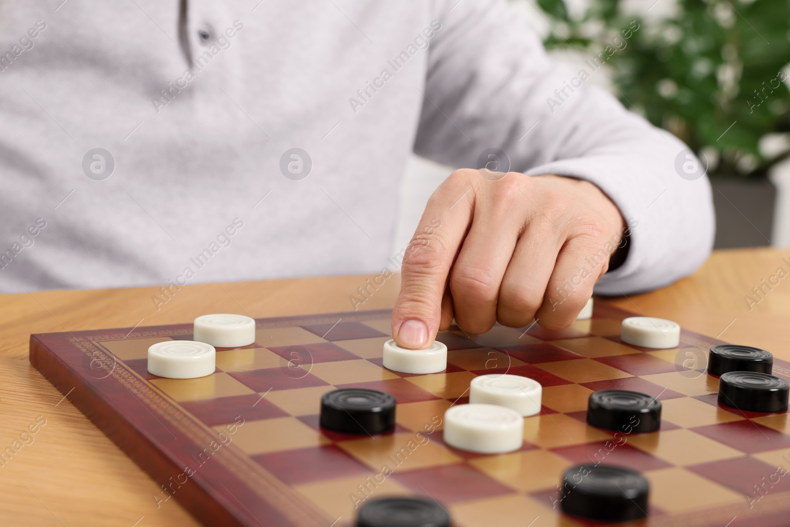 Photo of Playing checkers. Senior man thinking about next move at table in room, closeup