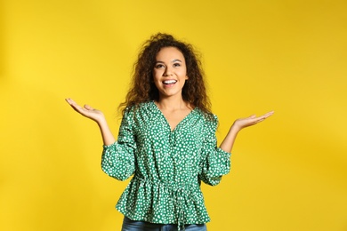 Portrait of emotional African-American woman on color background