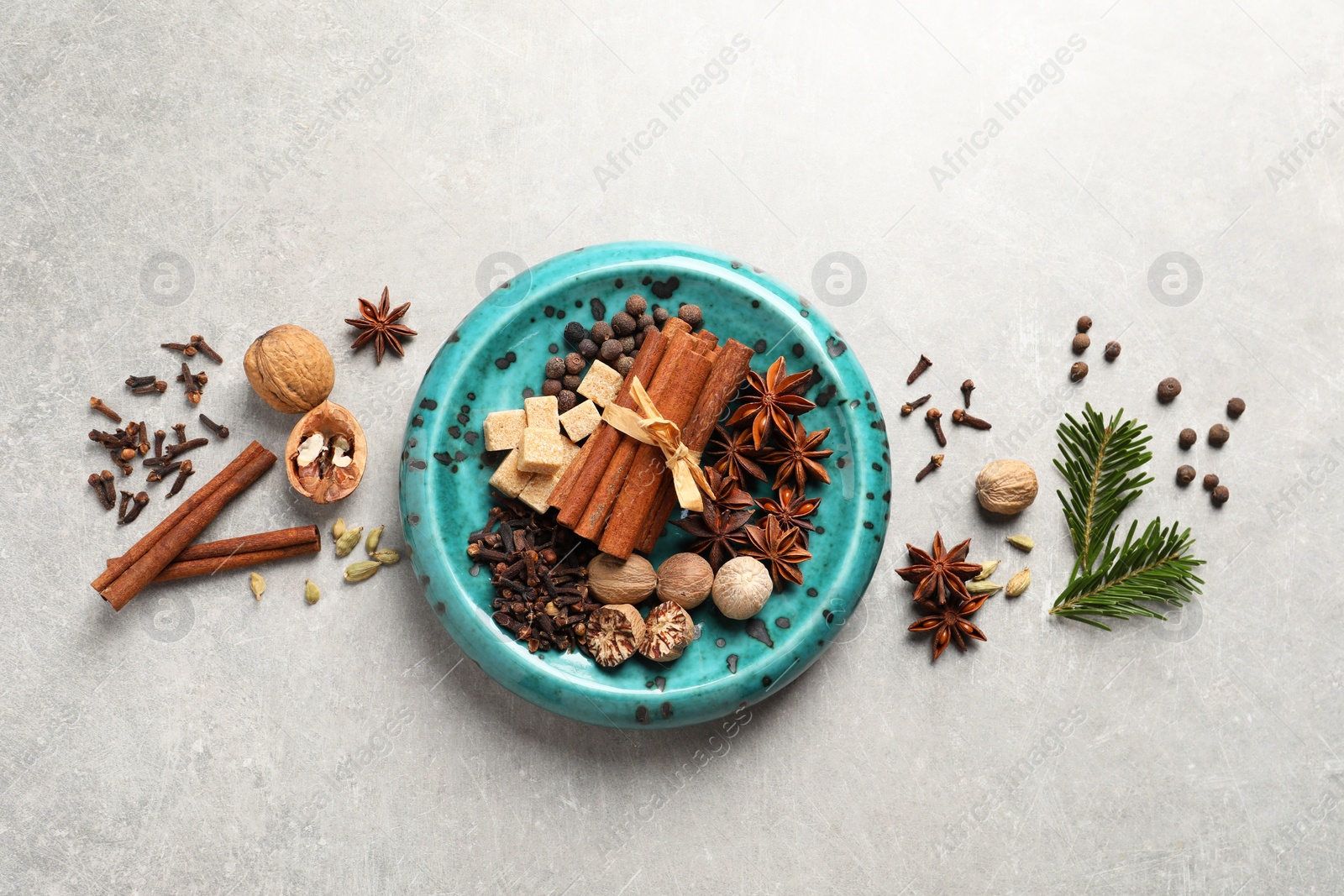 Photo of Different aromatic spices and fir branches on light textured table, flat lay