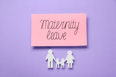 Photo of Card with phrase Maternity Leave and figures of family on violet background, flat lay