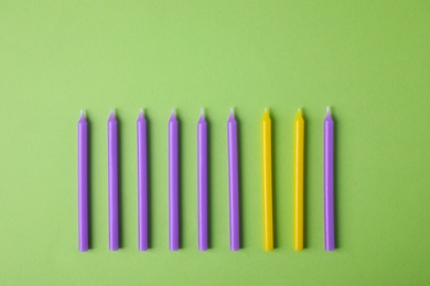 Photo of Colorful birthday candles on green background, flat lay