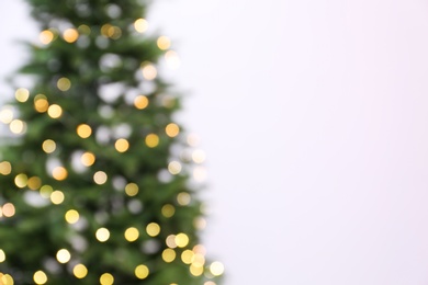 Photo of Blurred view of beautiful Christmas tree with fairy lights on white background