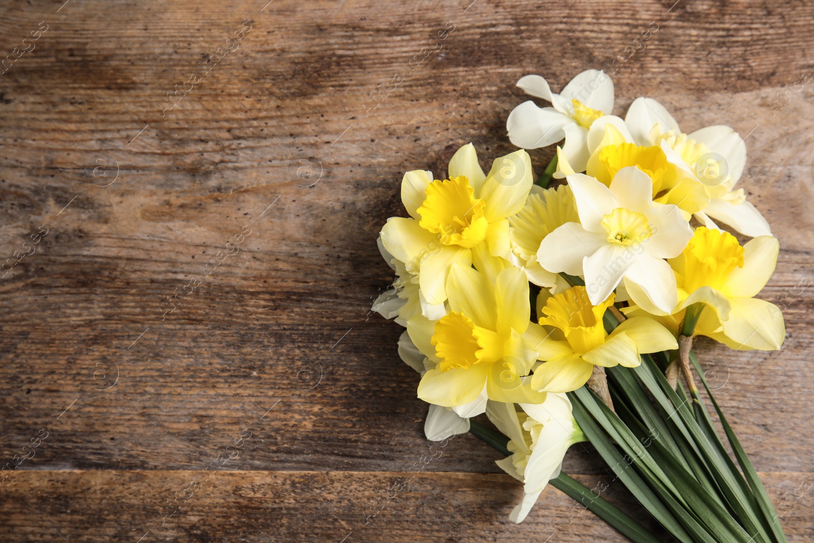 Photo of Bouquet of daffodils on wooden background, top view with space for text. Fresh spring flowers