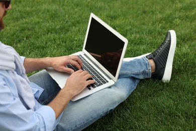 Photo of Man with laptop on green grass outdoors, closeup