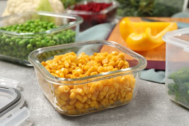 Photo of Containers with corn and fresh products on light gray table. Food storage
