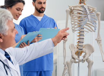 Photo of Professional orthopedist teaching medical students in clinic, closeup