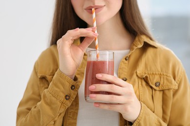 Photo of Beautiful young woman drinking delicious smoothie, closeup