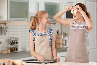 Photo of Mother and her daughter with cookie dough in kitchen