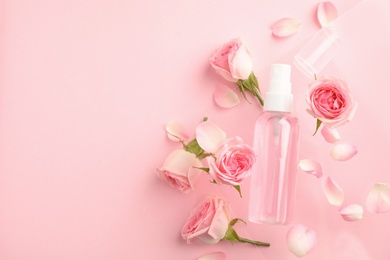 Photo of Flat lay composition with rose essential oil and flowers on pink background, space for text