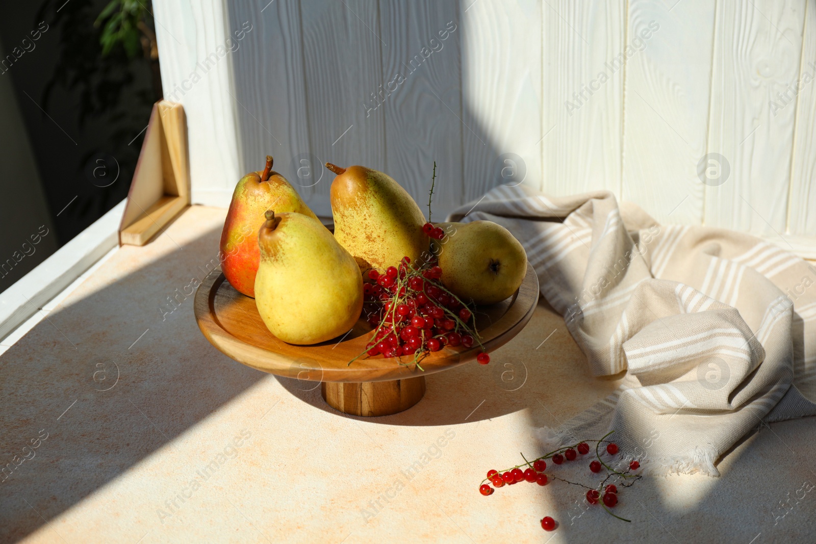 Photo of Stand with juicy pears, red currants and double-sided backdrop in photo studio