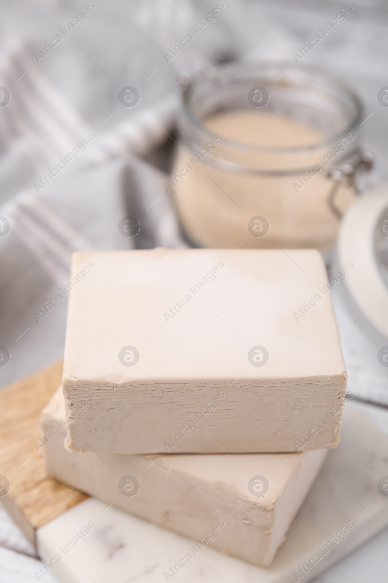 Photo of Blocks of compressed yeast on white wooden table, closeup