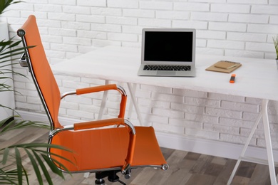 Photo of Comfortable workplace with office chair and wooden table