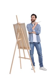 Photo of Happy man painting against white background. Using easel to hold canvas