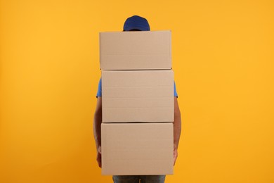 Photo of Courier with stack of parcels on orange background