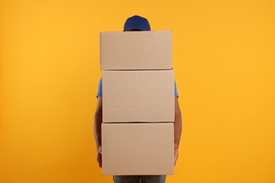 Courier with stack of parcels on orange background