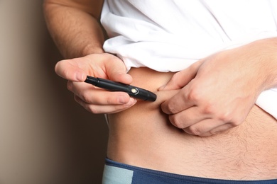 Photo of Man doing insulin injection in stomach, closeup. Diabetes disease