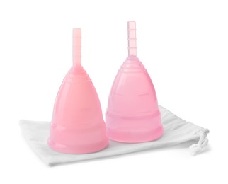 Photo of Pink menstrual cups with cotton bag on white background