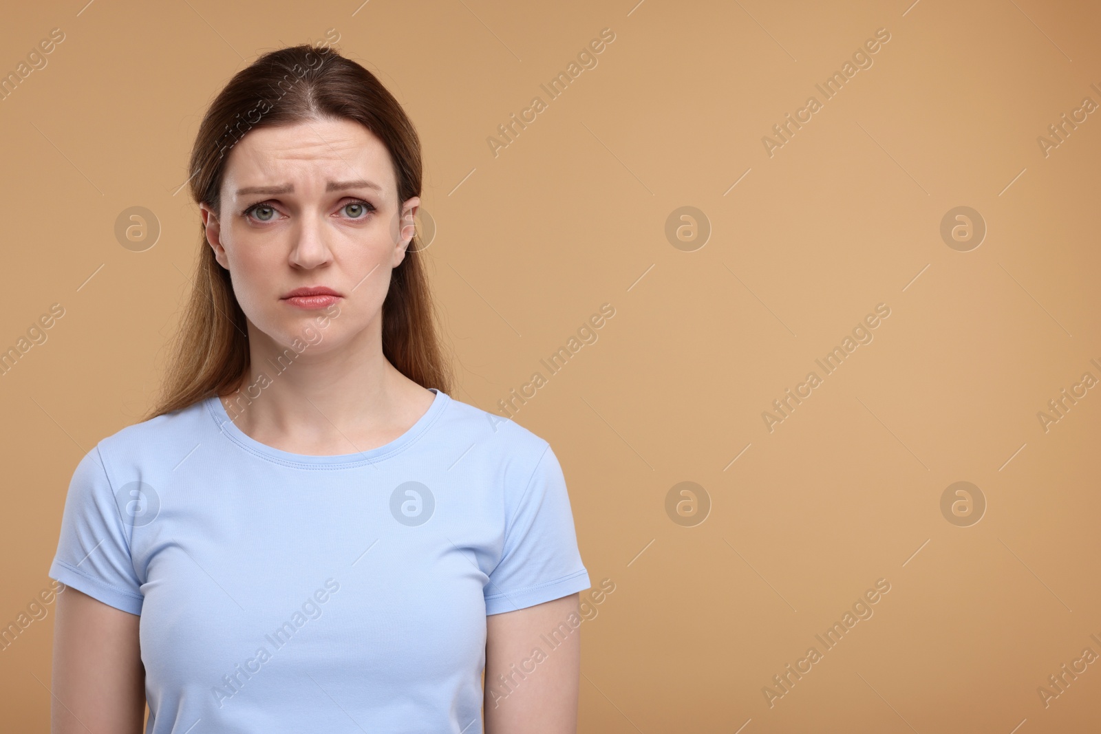 Photo of Portrait of sad woman on beige background, space for text