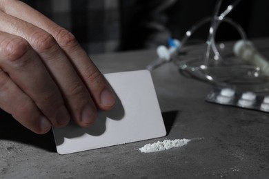 Addicted man preparing drugs for consumption at grey table, closeup