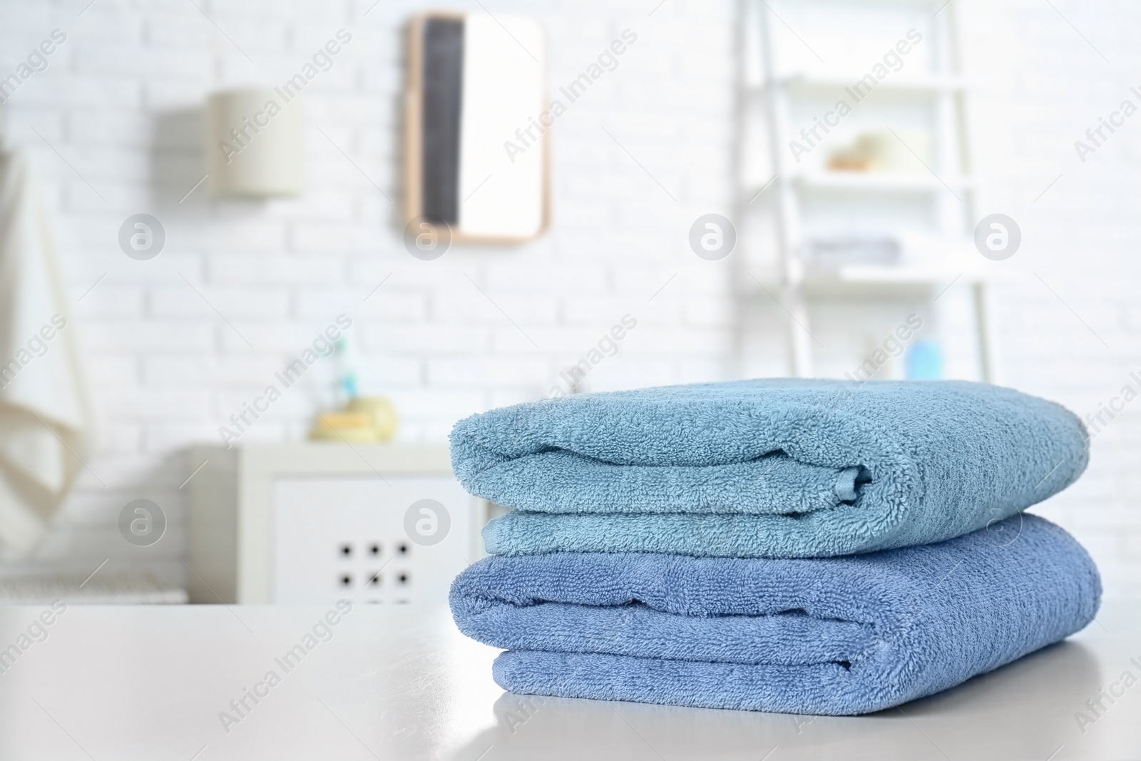 Photo of Stack of fresh towels on table in bathroom. Space for text