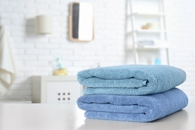 Stack of fresh towels on table in bathroom. Space for text