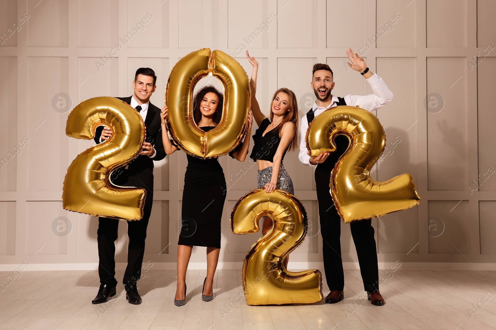 Photo of Happy friends with golden 2022 balloons indoors. New Year celebration