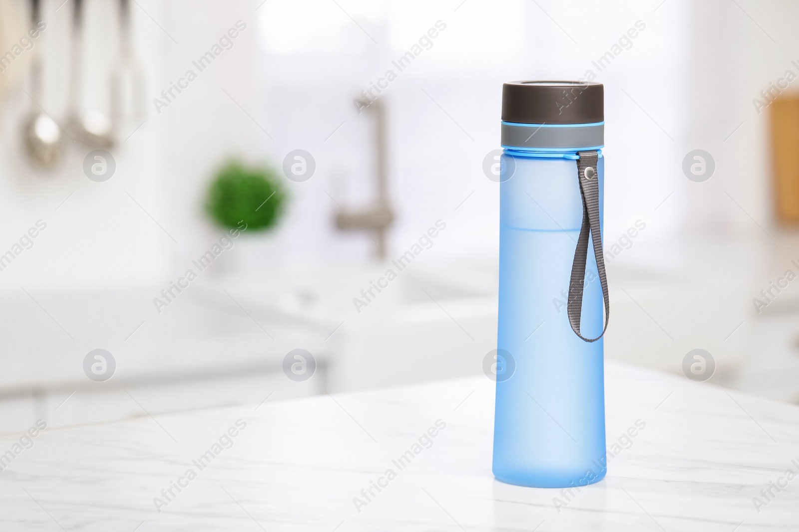 Photo of Stylish bottle of water on table in kitchen. Space for text