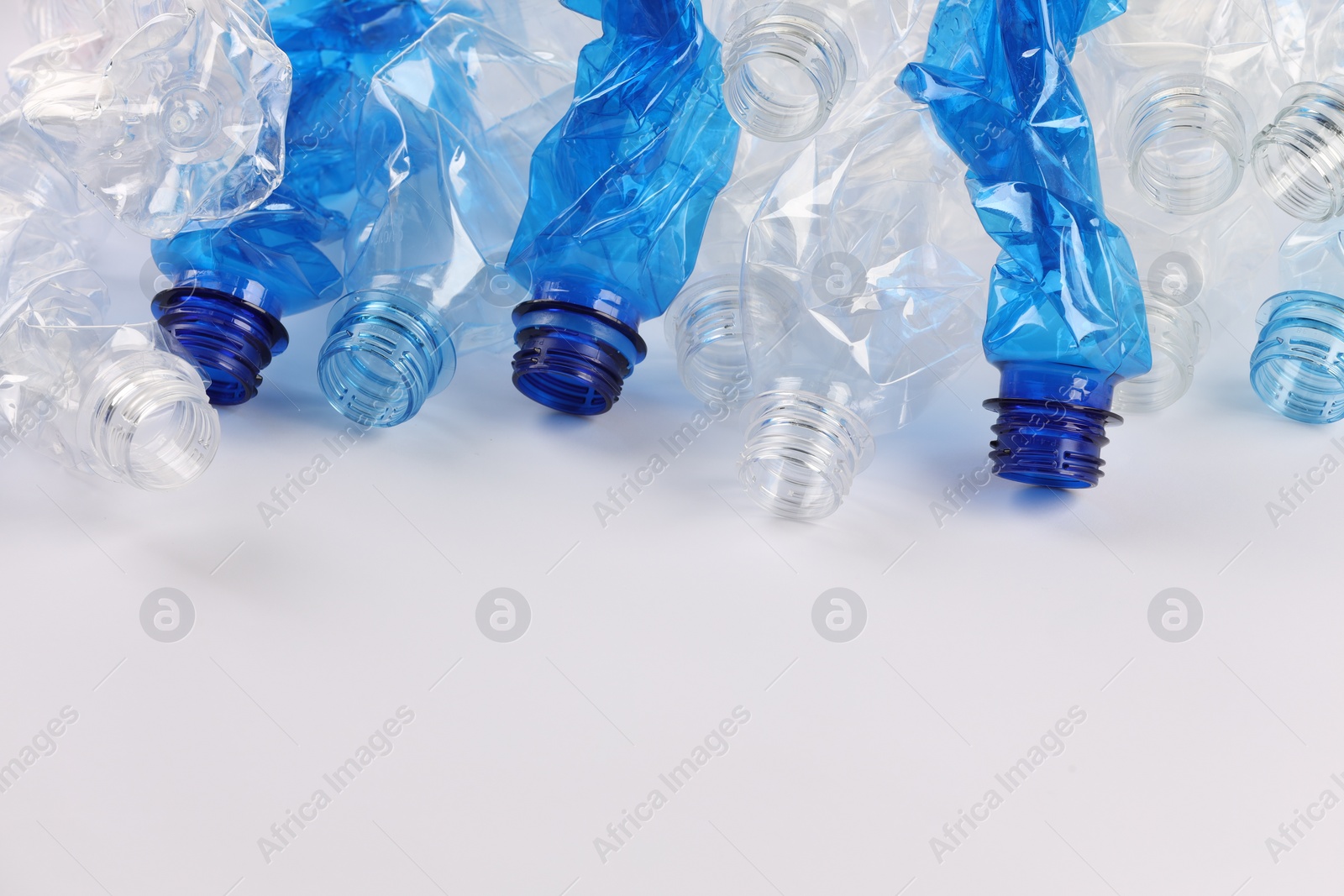 Photo of Crumpled disposable plastic bottles on white background, space for text