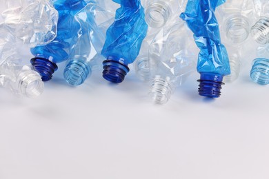 Crumpled disposable plastic bottles on white background, space for text