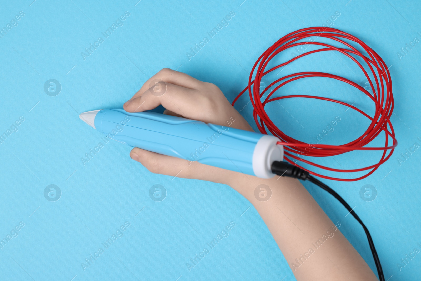 Photo of Boy drawing with stylish 3D pen on light blue background, top view